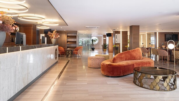 Un hall d’entrée moderne avec un comptoir d’accueil, des fauteuils confortables et un grand miroir.