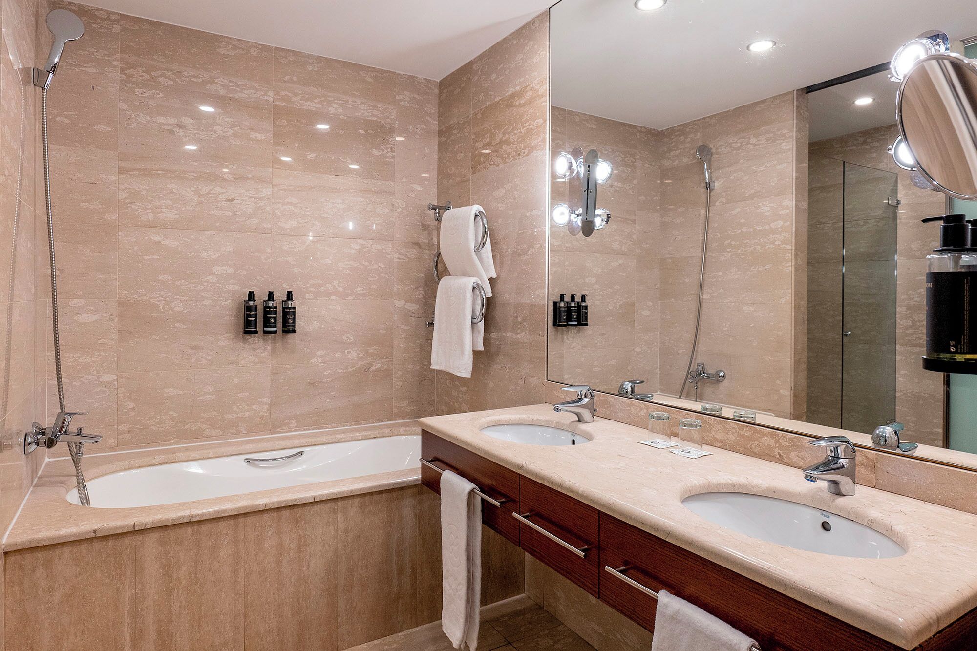 Une salle de bain moderne avec deux lavabos, une baignoire et un grand miroir.
