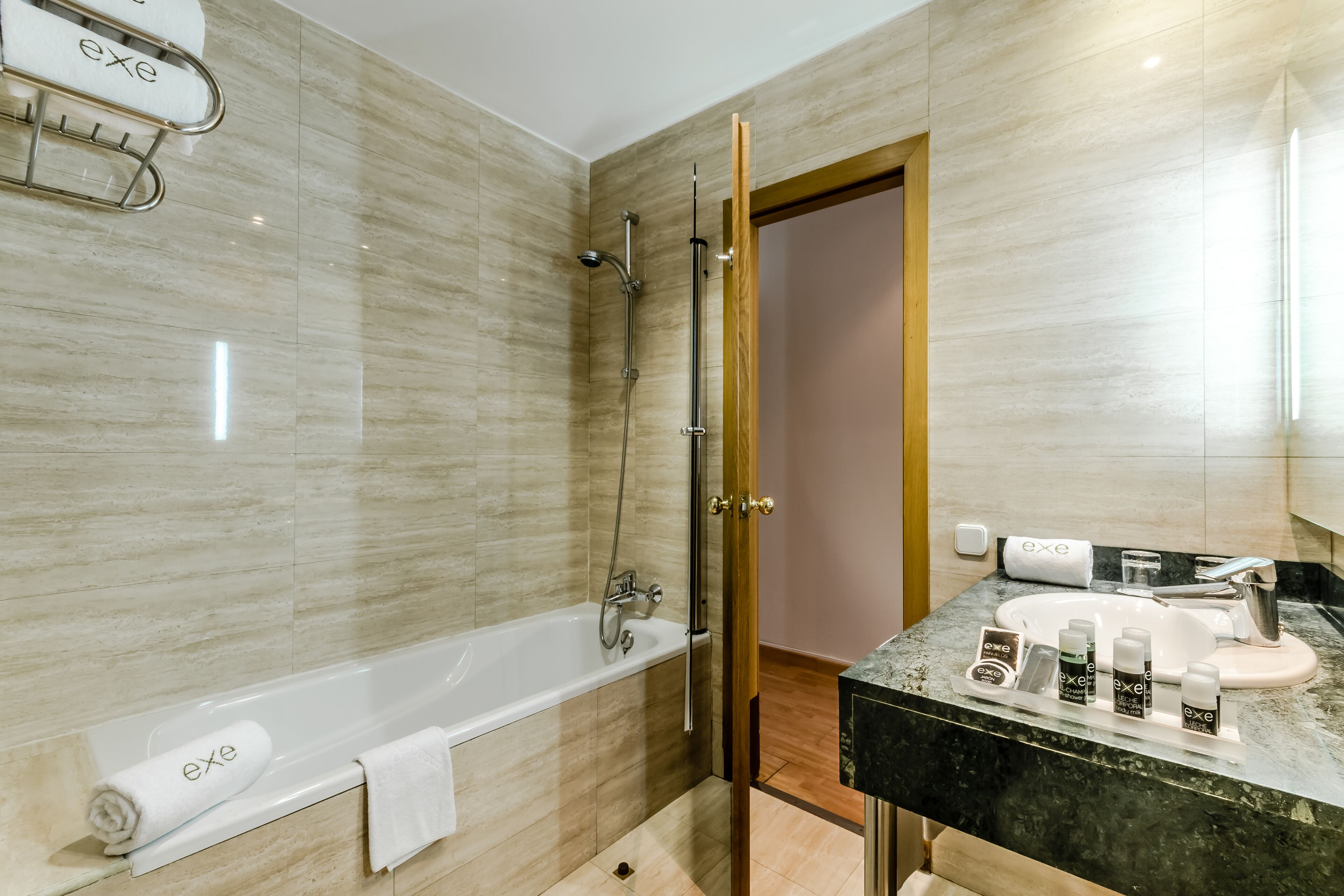 A modern bathroom with a bathtub, shower, and vanity with toiletries.