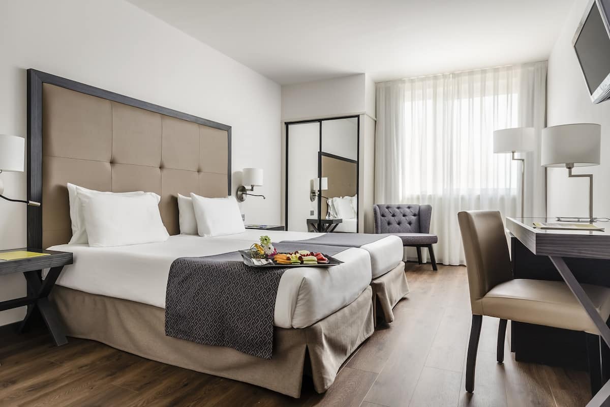 Habitación de hotel con una cama grande, un escritorio, una silla y un televisor.