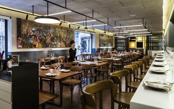 A restaurant with long wooden tables, chairs, and a mural on the wall. - Park Hotel Barcelona (Barcelona)