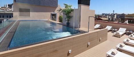 Una piscina al aire libre, sillones reclinables de piscina