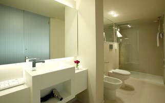 Une salle de bain moderne avec un lavabo blanc, un miroir et une cabine de douche en verre.