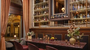 A bar area with a marble countertop, multiple shelves of bottles, and bar stools. - Porta Rossa Hotel Firenze Colbert Collection (Florence)