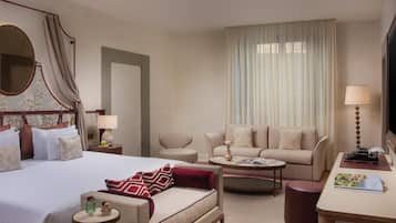Una habitación de hotel con cama, sofá, mesa de centro, escritorio y televisor.