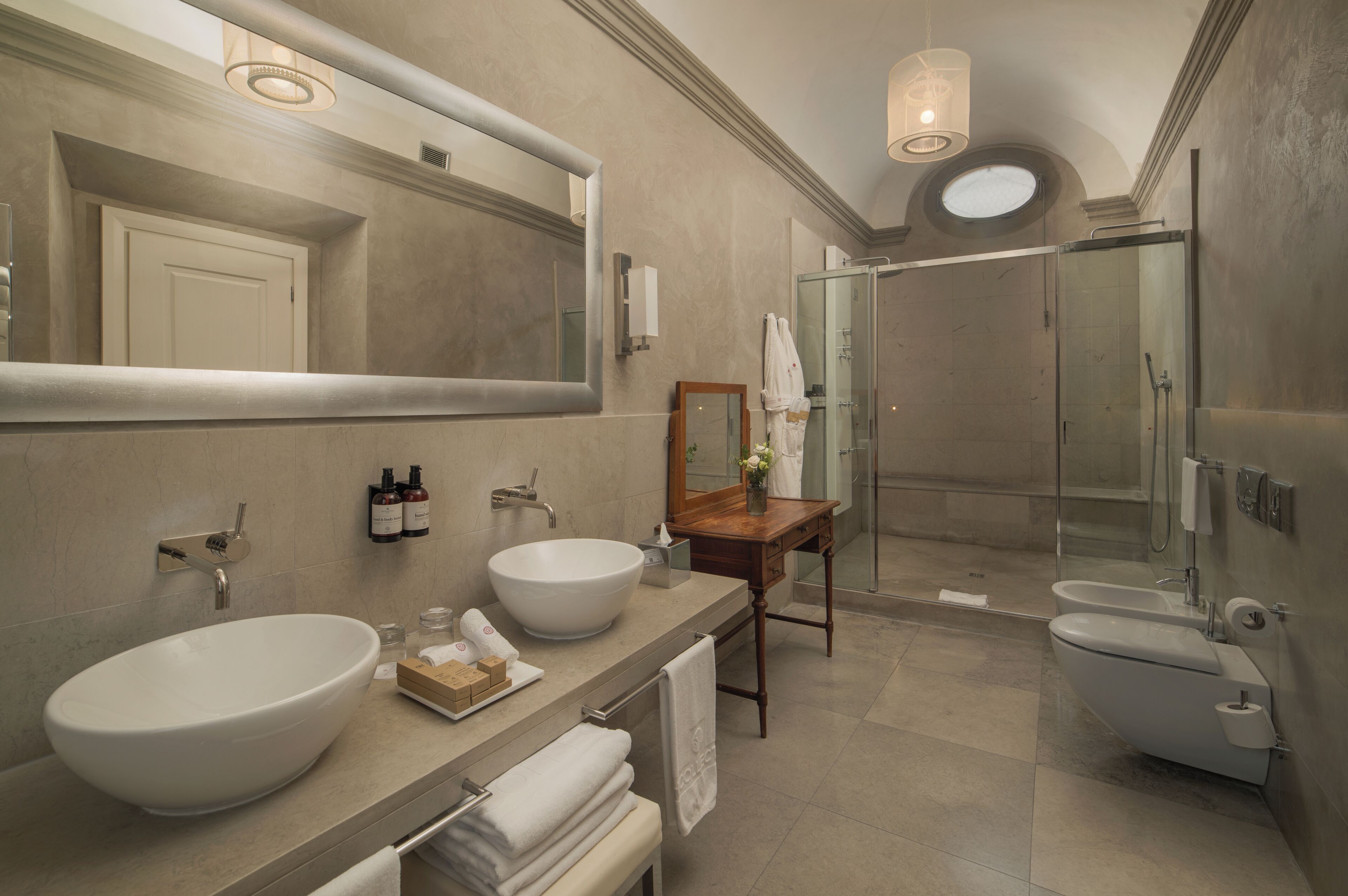 A bathroom with a large mirror, a vessel sink, a wooden vanity, a glass shower enclosure, and a toilet.