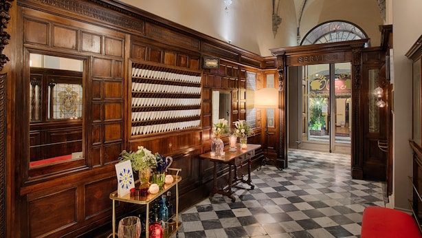 A checkered floor, wooden paneling, a service desk, and a chandelier. - Porta Rossa Hotel Firenze Colbert Collection (Florence)