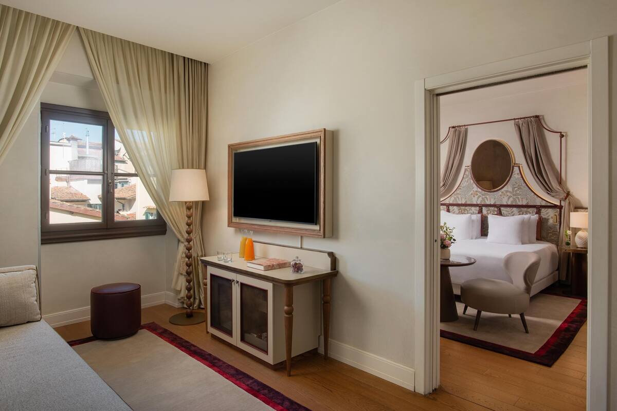 Une chambre d’hôtel avec un lit, une télévision, un bureau avec une lampe et une vue sur les bâtiments environnants.