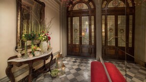 A grand hallway with a checkered floor, a red bench, and a large ornate mirror. - Porta Rossa Hotel Firenze Colbert Collection (Florence)
