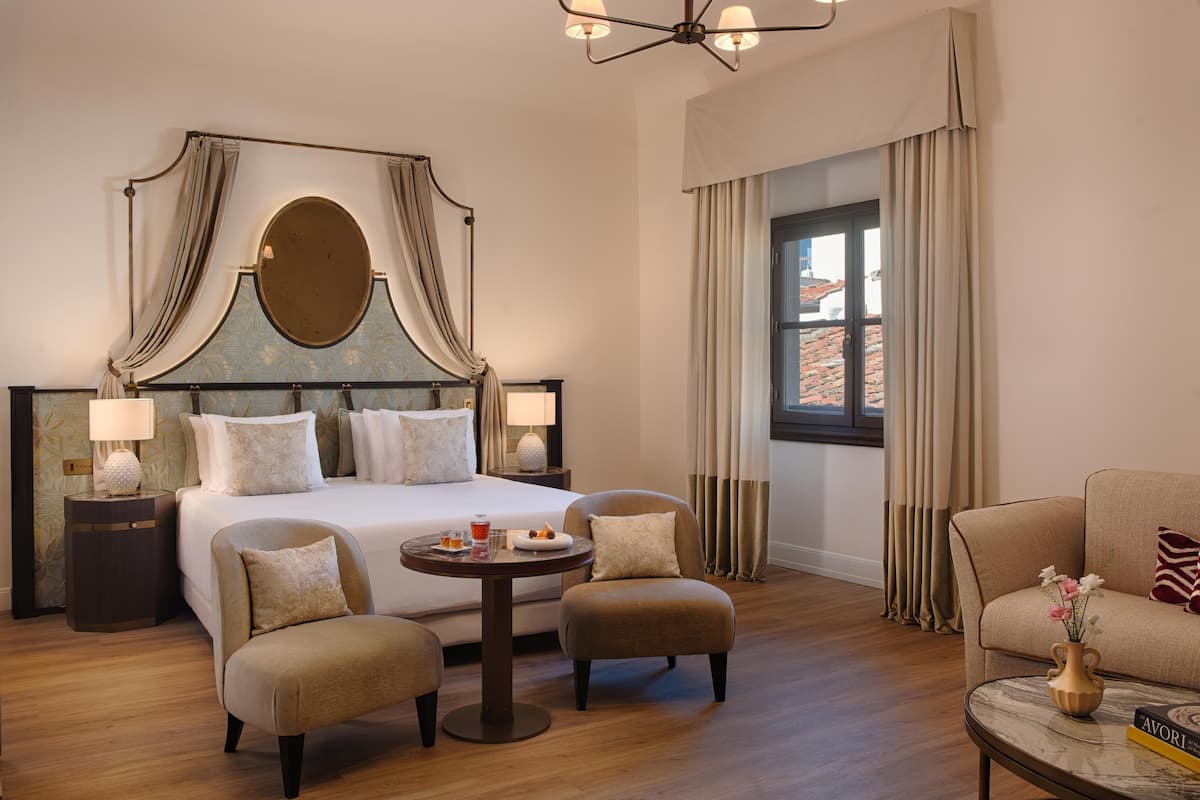Une chambre d’hôtel avec un grand lit, deux fauteuils, une petite table ronde et un canapé.