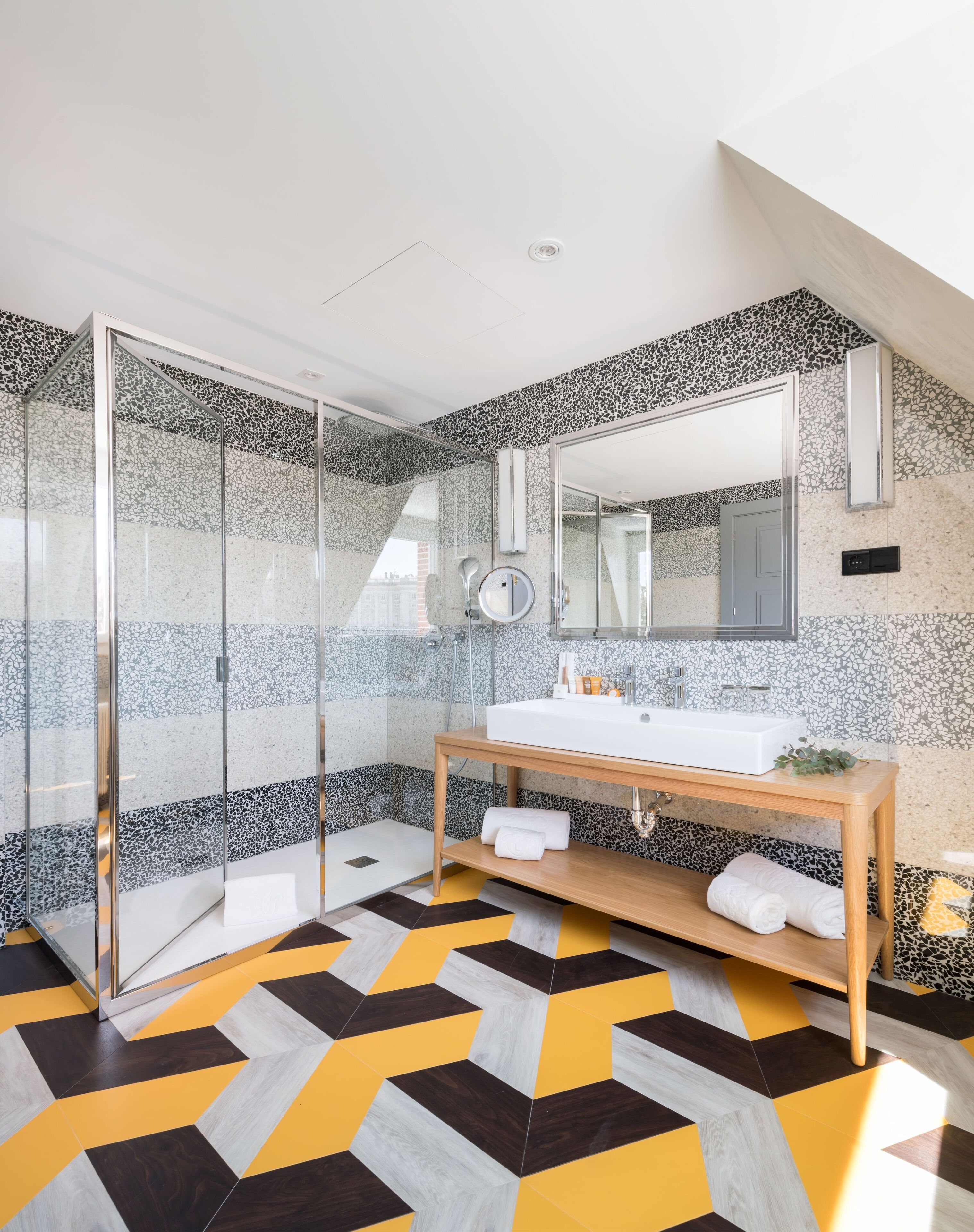 Un baño moderno con cabina de ducha de vidrio, un lavabo blanco y un espejo.