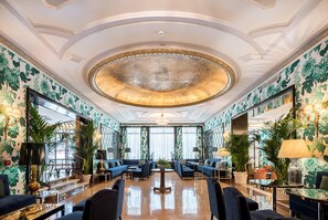 A spacious lobby with a grand chandelier, comfortable seating, and large windows.