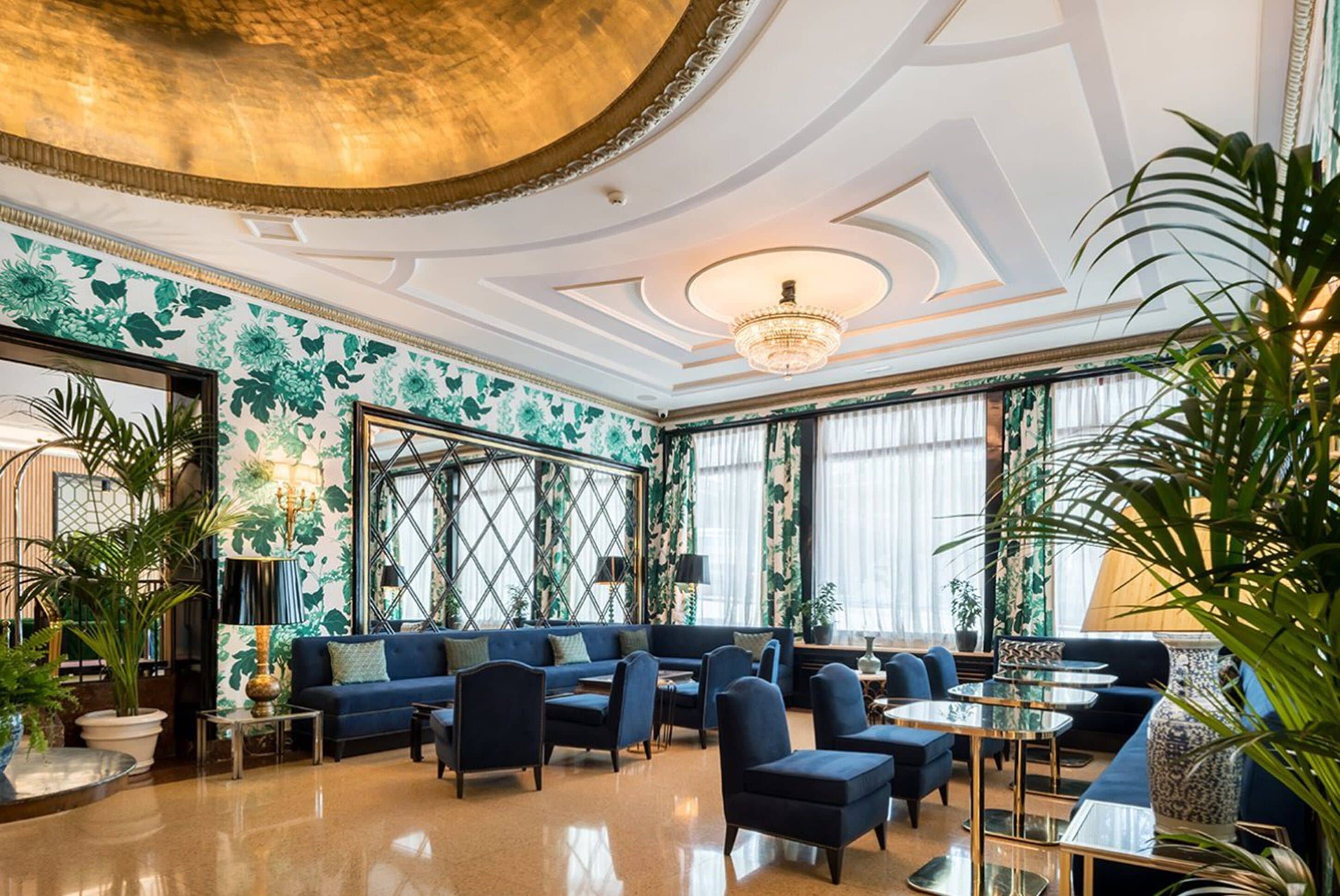 Un'ampia hall con un divano blu, poltrone e un lampadario.. Hotel Principe Pio