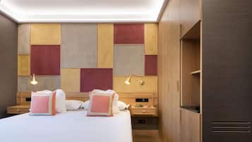 Una habitación de hotel moderna con una cama grande, mesitas de noche, un armario de madera y una pared con diseños geométricos.