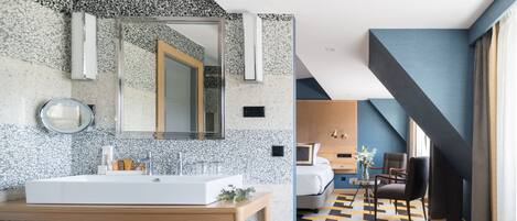 Un baño moderno con un espejo grande, lavamanos blanco y un mueble de tocador de madera.