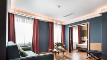 Una habitación de hotel moderna con un sofá, una mesita con un florero y una cama.
