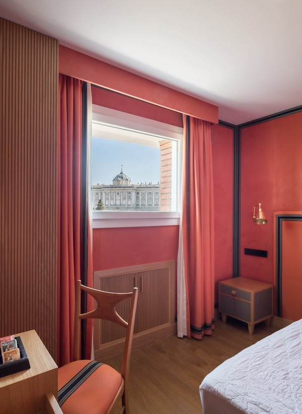 A hotel room with a large window, a wooden chair, a bedside table, and a bed. - Hotel Principe Pio (Madrid)