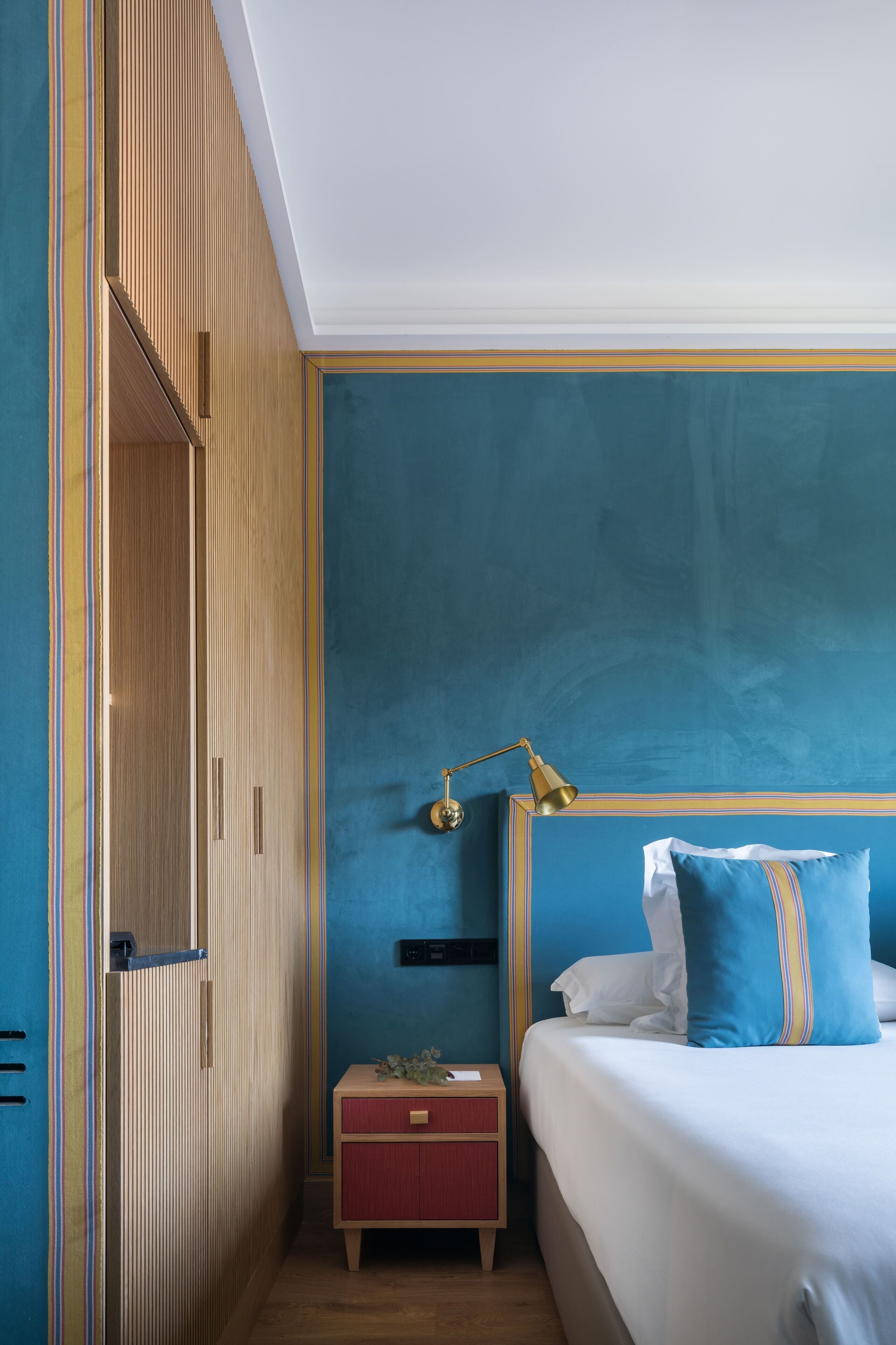 A bedroom with a bed, a nightstand, a lamp, and a wardrobe.