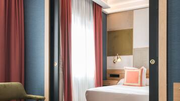Una habitación de hotel con una cama, una silla y un espejo.