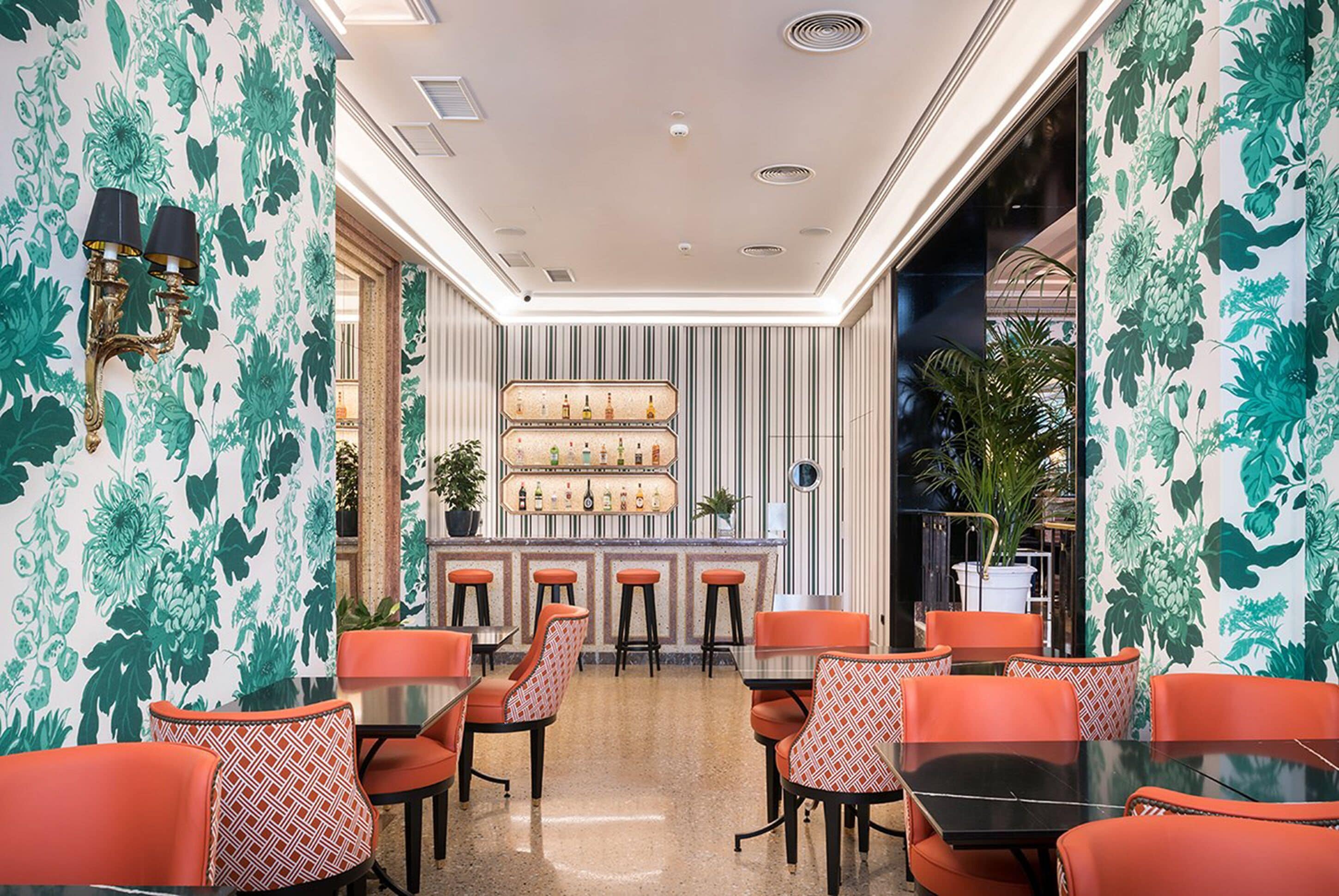 A bar area with stools, a counter with bottles, and a patterned wall.
