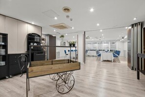 A modern interior with a wooden cart, a kitchenette, and a dining area with tables and chairs. - Hotel Zentral Ramiro I Oviedo (Oviedo)
