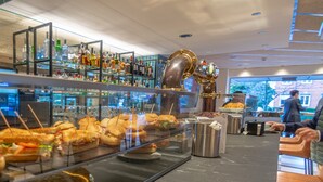 A restaurant with a glass display case of sandwiches and a bar area with shelves of bottles. - Hotel Zentral Ramiro I Oviedo (Oviedo)