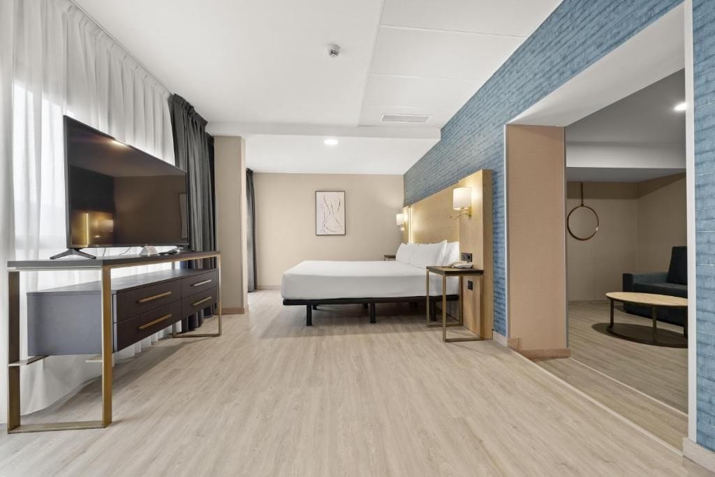 A hotel room with a bed, desk, and seating area.