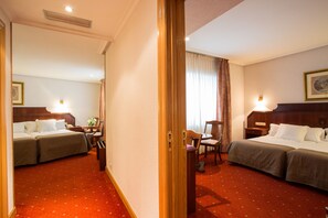 A hotel room with two beds, a desk, a chair, and a window with curtains. - Hotel Zentral Ramiro I Oviedo (Oviedo)