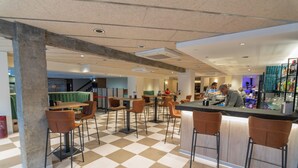 A modern cafe with a checkered floor, bar area with stools, and a seating area with tables and chairs. - Hotel Zentral Ramiro I Oviedo (Oviedo)