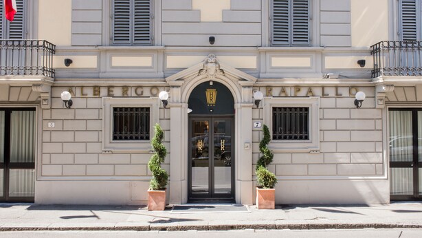 Un edificio con fachada clásica, que presenta una entrada central con puerta negra y un letrero encima.