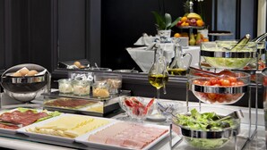 Un bufé con diversos alimentos, incluyendo carnes, quesos y ensaladas.