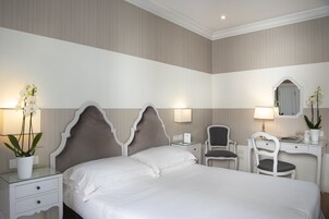 Una habitación de hotel con una cama grande, dos mesitas de noche, un escritorio, una silla y un espejo.