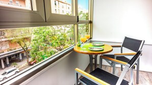 A corner room with a balcony, a table with plates and glasses, and a chair. - Hotel Regio Cadiz (Cádiz)