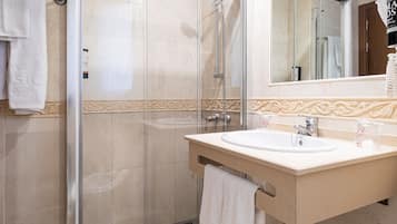 Un bany modern amb un espai de dutxa de vidre, un lavabo amb calaixeria i un mirall.