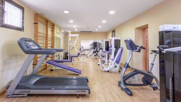 Ein Fitnessraum mit Laufbändern, Kraftgeräten und einer Holzwand.