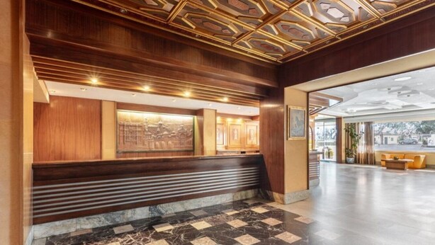 Vestíbulo con mostrador de recepción, suelo de mármol y techo decorativo.