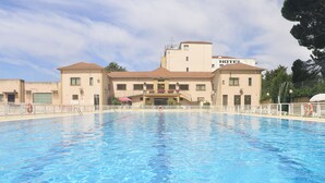 Un hotel con piscina, zona cubierta y cielo despejado.