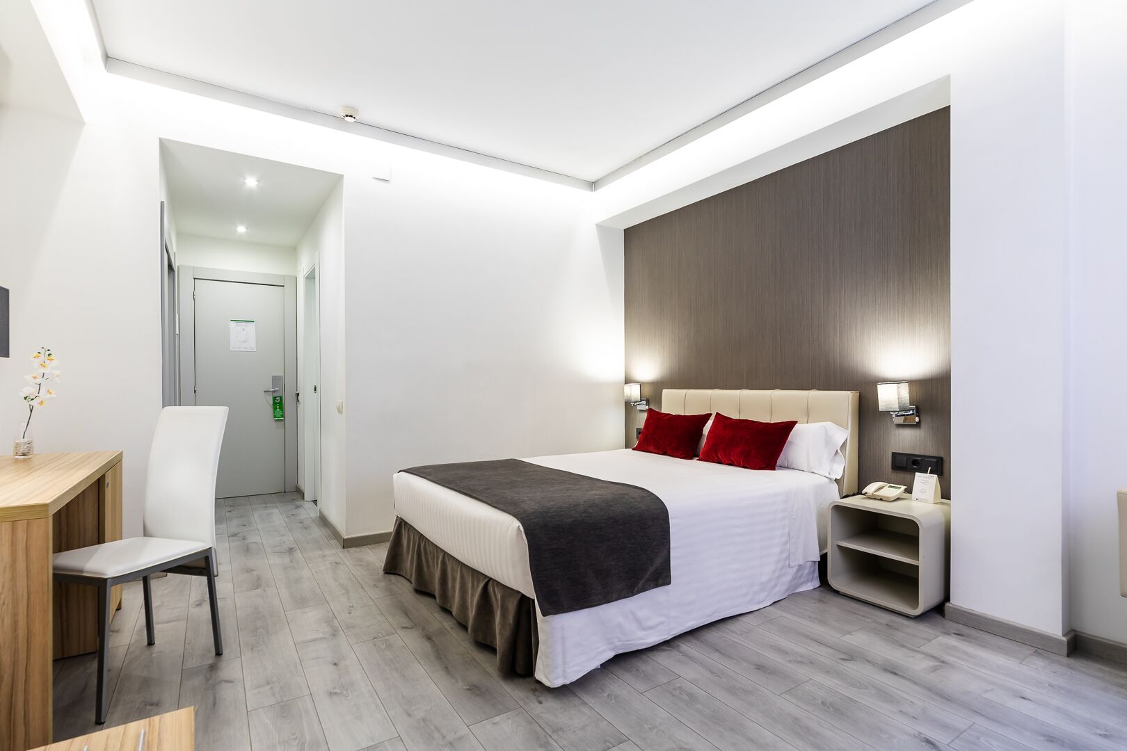 Una habitación de hotel moderna con una cama grande, mesitas de noche, un escritorio y una silla.