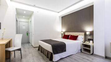 Una habitación de hotel moderna con una cama grande, mesitas de noche, un escritorio y una silla.