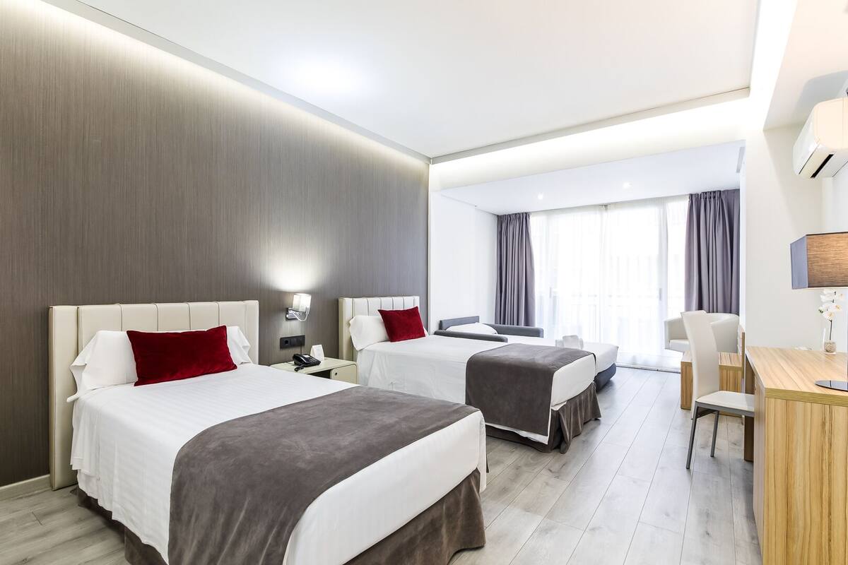 A hotel room with two beds, a desk, and a chair.