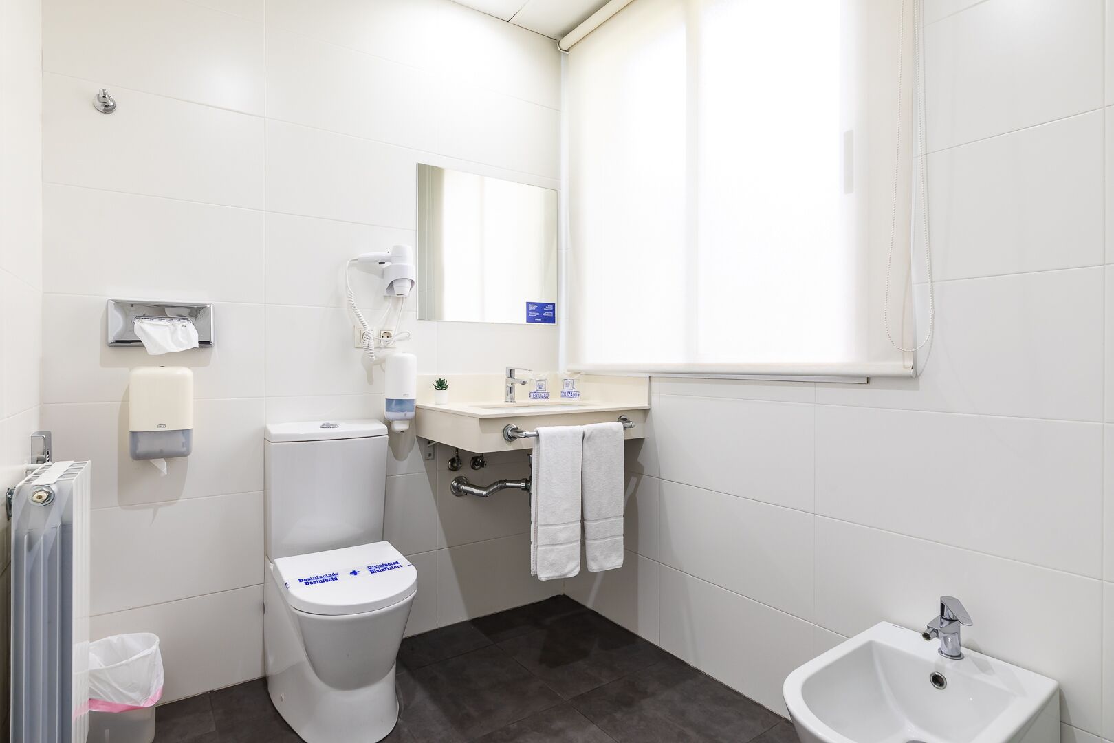 Une salle de bain moderne équipée de toilettes, d’un lavabo, d’un bidet et d’un robinet pour bidet.