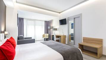 Una habitación de hotel moderna con una cama grande, un escritorio, una silla, un televisor y un espejo.