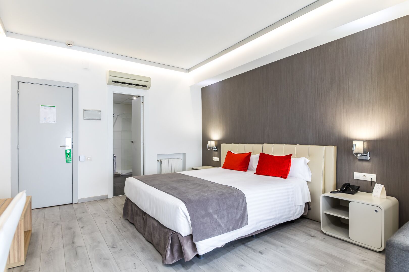 A modern hotel room with a large bed, bedside tables, a desk, and a shower area.
