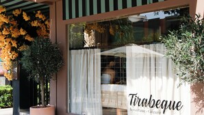 A restaurant entrance with a large glass window, a sign reading "Tirabeque Restaurante - Cafetería", and potted plants on either side. - Sweet Hotel Renasa (Valencia)