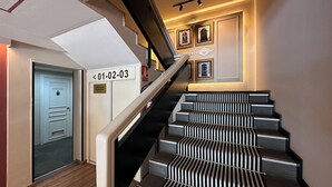 A staircase with black and white striped steps, a handrail, and a wall with framed pictures. - Sweet Hotel Renasa (Valencia)