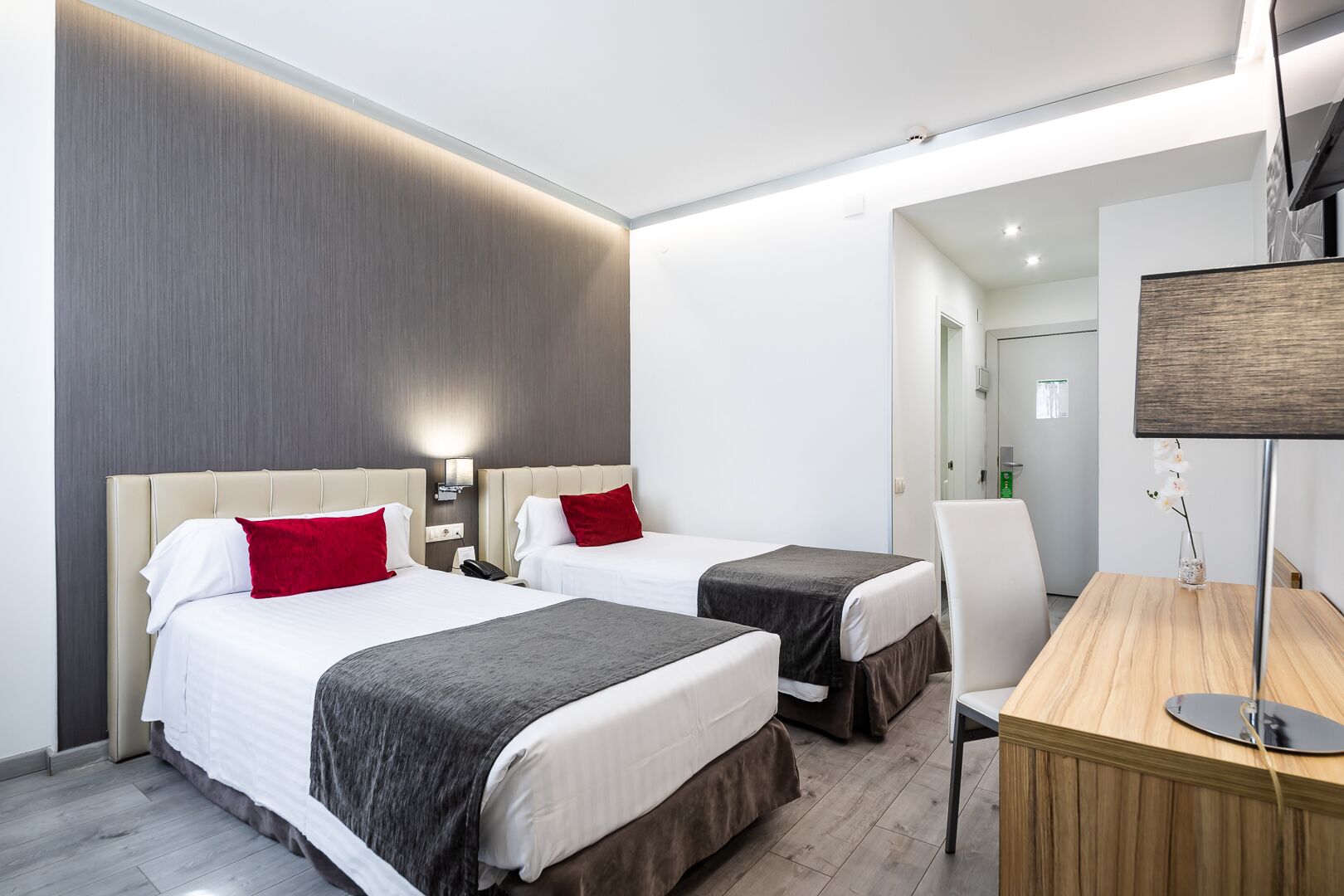 Habitación de hotel con dos camas, un escritorio y una silla.