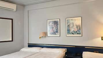 Una habitación de hotel con una cama, dos lámparas de pared y dos cuadros enmarcados.