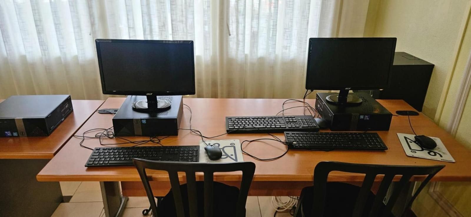 Un espacio de trabajo con dos monitores, dos teclados y dos sillas.