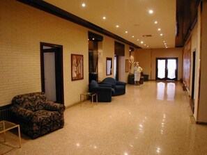 A hotel lobby with a brick wall, a reception desk, and a person in a uniform.