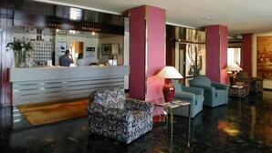 Un hall d’entrée avec un comptoir de réception, un espace salon et un sol en marbre.